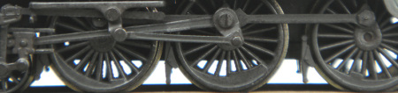 A close-up of a steam engine under frame that shows the difference in tone with greasy wheels.